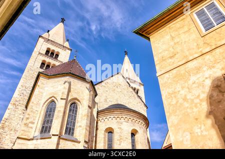 Le torri romaniche della basilica di San Giorgio si innalzano sopra i cortili del Castello di Praga, una delle più antiche strutture ecclesiastiche sopravvissute della città Foto Stock