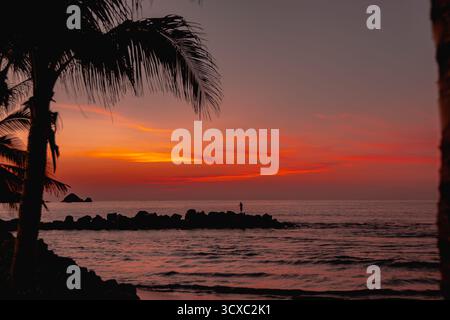 Due pescatori locali gettano le loro file lungo Playa Linda a Ixtapa, Messico, durante un caldo tramonto tropicale sulla costa del Pacifico. Foto Stock