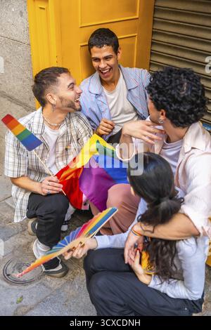 Gruppo di giovani amici adulti che si godono un momento di connessione all'aperto, tenendo bandiere arcobaleno ed esprimendo gioia, rappresentando la comunità, EQUAL Foto Stock
