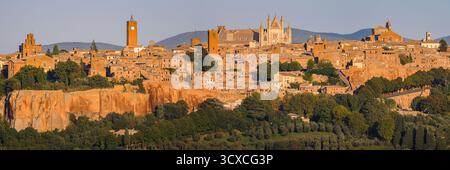 La calda luce del tramonto illumina lo storico skyline di Orvieto, Italia. La cittadina medievale in cima a una collina si illumina dolcemente in cima al suo altopiano vulcanico di tufo, circondato da un paesaggio Foto Stock