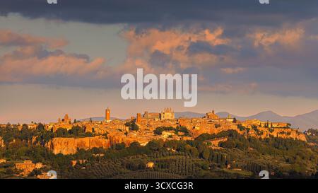 Spettacolare tramonto su Orvieto, Italia, con spettacolari nuvole che torreggiano sopra lo skyline medievale. Le sfumature dorate e arancioni del sole che tramonta illumi Foto Stock