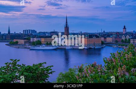 Stoccolma, Svezia - 4 giugno 2025: Una vista panoramica di stoccolma, svezia al crepuscolo, con edifici storici, una guglia da chiesa e acque calme Foto Stock