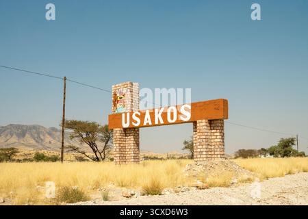 Una vista panoramica di un cartello stradale che porta a Usakos, Namibia - 2 settembre, adagiato su un cielo azzurro luminoso e una strada aperta. L'immagine cattura l'essenza o Foto Stock