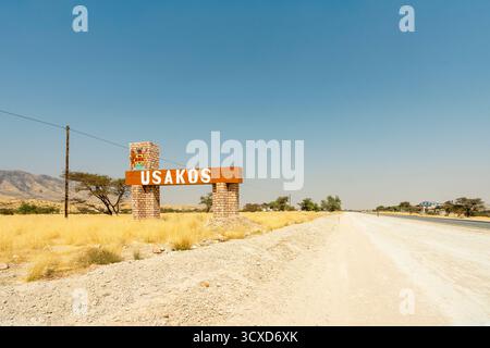 Una vista panoramica di un cartello stradale che porta a Usakos, Namibia - 2 settembre, adagiato su un cielo azzurro luminoso e una strada aperta. L'immagine cattura l'essenza o Foto Stock