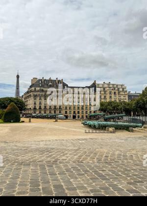 Ampia vista dell'Esplanade des invalides di Parigi, con antichi cannoni militari, edifici Haussmanniani e la lontana Torre Eiffel Foto Stock