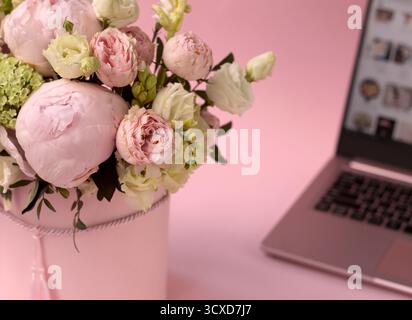 bouquet di fiori in una scatola da primo piano, sullo sfondo di un laptop aperto Foto Stock