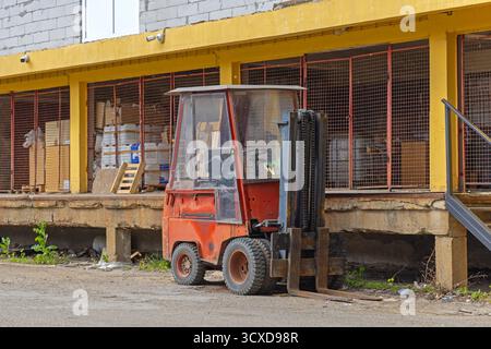 Piccolo carrello elevatore a forche di fronte al magazzino di stoccaggio della baia di carico Foto Stock