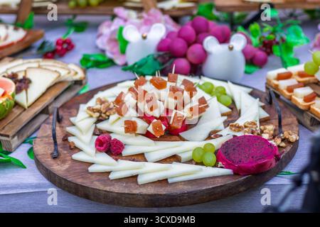 Vassoio di formaggi con vari formaggi, pasta di cotogna, noci, uva, lamponi, e frutta di drago, perfetta per il catering Foto Stock