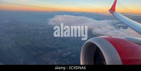Vista dalla finestra dell'aereo al tramonto con motore e ala visibili. Foto Stock