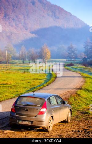 perechyn, ucraina - 10 novembre 2020: auto vicino alla strada asfaltata in autunno. viaggio attraverso il paesaggio di campagna montano dell'ucraina con la nebbia mattutina. cappello hyundai Foto Stock