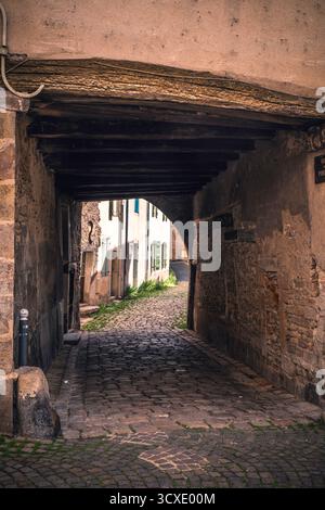 Storico passaggio ad arco sopra il vicolo acciottolato in un centro storico europeo Foto Stock