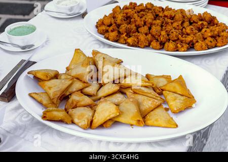 Deliziosi Samosas indiani e antipasti serviti su un piatto bianco Foto Stock