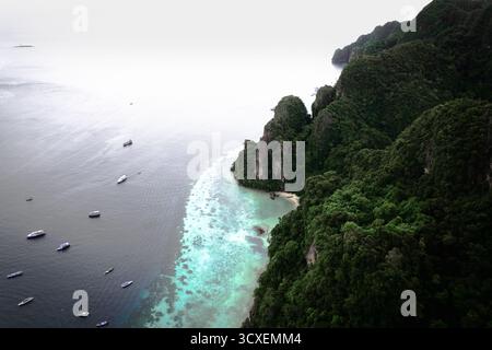 Splendida vista aerea delle acque color smeraldo, delle barriere coralline e delle scogliere calcaree ricoperte di vegetazione nella giungla vicino a Maya Bay, Phi Phi Leh, Thailandia. Foto Stock