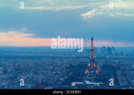 Parigi, 15 maggio 2024: La Torre Eiffel si illumina al crepuscolo, affacciata sul paesaggio urbano illuminato di Parigi. Foto Stock