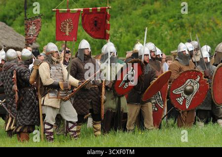 Gruppo di reenattori medievali con scudi e striscioni durante una mostra di battaglia del primo medioevo presso il museo archeologico all'aperto Karpacka Troja Foto Stock