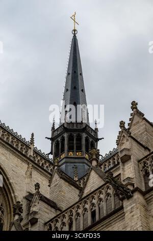 Primo piano della guglia gotica della chiesa di San Pietro sul Grote Markt, sormontata da un gallo dorato sotto un cielo nuvoloso. Foto Stock