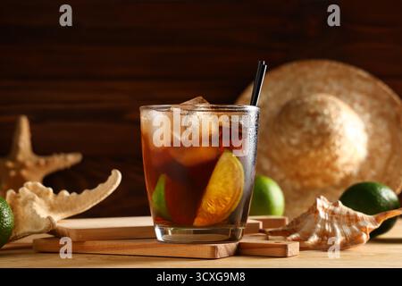 Bicchiere di cocktail Cuba Libre freddo con conchiglia e stelle marine su sfondo di legno Foto Stock