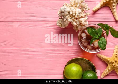 Bicchiere di cocktail Cuba Libre freddo con stelle marine e corallo su sfondo di legno Foto Stock