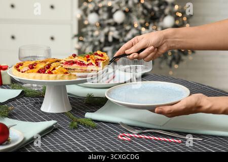 Donna che prende un pezzo di deliziosa torta di mirtilli nella camera decorata a Natale Foto Stock