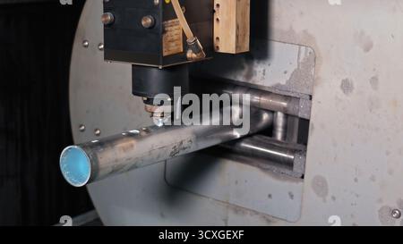 Macchina da taglio laser che elabora il tubo metallico. Primo piano di una macchina da taglio laser industriale che esegue con precisione i fori in un tubo metallico cilindrico Foto Stock