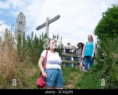 Gruppo di famiglie all'attraversamento del sentiero pedonale, seguendo le indicazioni del National Trust sulla passeggiata costiera del Dorset Foto Stock