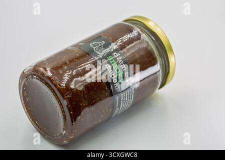 Porec, Croazia - 4 giugno 2025: Vaso di vetro di marmellata di fichi croati con miele, con coperchio dorato e etichetta scura, contiene crema di frutta conservata, closeu Foto Stock