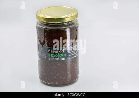 Porec, Croazia - 4 giugno 2025: Vaso di vetro di marmellata di fichi croati con miele, con coperchio dorato e etichetta scura, contiene crema di frutta conservata, closeu Foto Stock