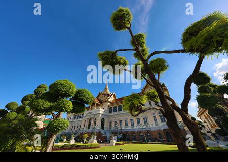 Edificio Phra Thinang Dusit Maha Prasat e guglia nei giardini e topiario del complesso del Grand Palace, Wat Phra Kaew, Bangkok, Thailandia. Foto Stock