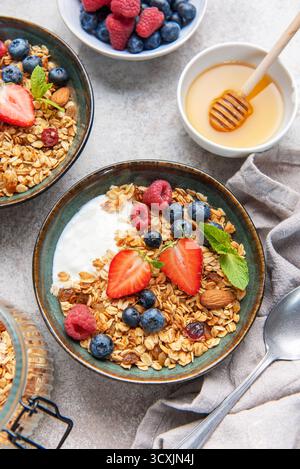 Ciotole di muesli con fragole fresche, mirtilli, lamponi, yogurt, noci, e miele per una colazione sana Foto Stock