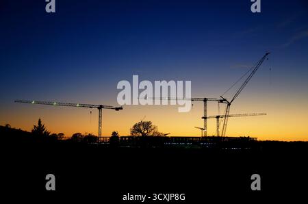 Le gru da costruzione creano sagome sullo splendido cielo serale al tramonto. Copia spazio. Foto Stock