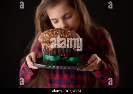 Ragazza che tiene in mano il panettone italiano, concetto per le vacanze di Natale, cottura fatta in casa, tradizione e cibo Foto Stock