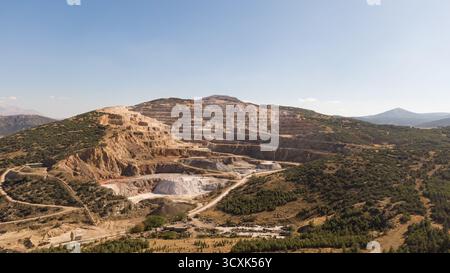 Una grande miniera a cielo aperto o cava in un'area rurale montana con strati a gradini. Cava di materie prime per una fabbrica di cemento. Miniere, ambiente, indust Foto Stock