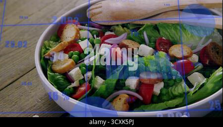 Esposizione di un recipiente per insalate in ceramica con verdure e pinze in legno sul tavolo da cucina, con griglia digitale Foto Stock