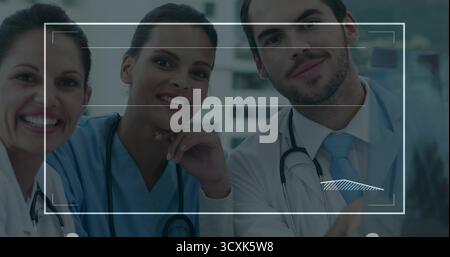 Esame di un team medico che analizza la sovrapposizione di scansioni radiografiche sul monitor nella sala esame, con stetoscopi Foto Stock
