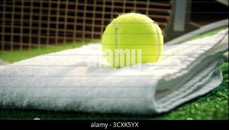 Palla da tennis riposante su un asciugamano bianco al campo da tennis, con rete da tennis arancione, palo in metallo Foto Stock