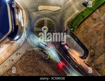 vista aerea dall'alto in basso intorno all'incrocio di notte, corsie illuminate e auto parcheggiate Foto Stock