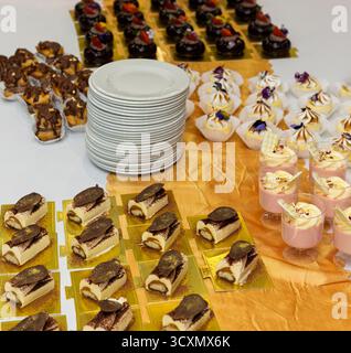 eclari di cioccolato, mousse di fragole, cupole, meringa, posti sul tavolo, scaglie d'oro commestibili in cima, avvolti in carta Foto Stock