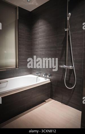 Bagno moderno dell'hotel con vasca e piastrelle di carbone opaco Foto Stock