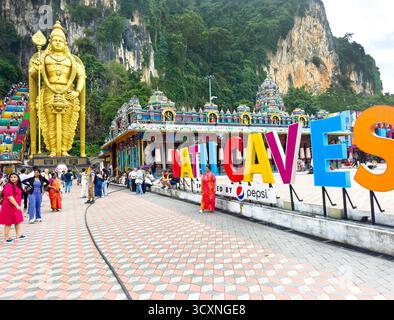 Il cartello d'ingresso alle grotte di Batu presenta la gigantesca statua dorata di Lord Murugan e le colorate scale del tempio contro una collina rocciosa di kuala lumpur in malesia Foto Stock