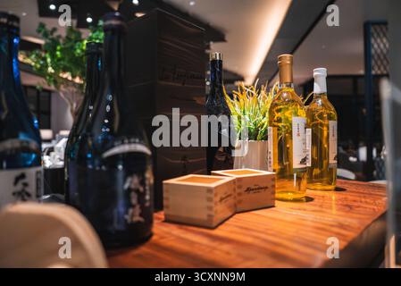 Bar di lusso in Giappone con bottiglie di sake, vino e tazze di masu Foto Stock