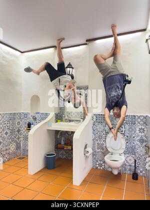 uomini e donne eseguono dei cavalletti acrobatici sul soffitto di un bagno capovolto con piastrelle a motivi geometrici. Foto Stock