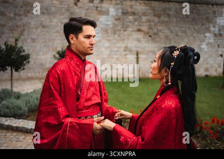 Giovane coppia che si tiene per mano mentre indossa abiti tradizionali cinesi hanfu Foto Stock