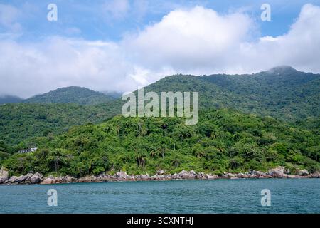 Lussureggianti colline tropicali, montagne e fitte foreste verdi si estendono attraverso il paesaggio sotto un cielo blu parzialmente nuvoloso Foto Stock