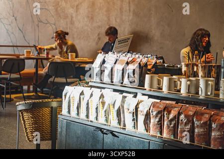 Interno della caffetteria Starbucks con persone sedute ai tavoli e selezione di pacchetti di caffè in primo piano Foto Stock