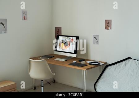 Moderno spazio di lavoro minimalista con computer desktop che mostra la natura morta di frutta Foto Stock