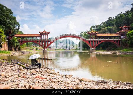 Leshan, Cina - 29 settembre 2018: Uomo che pesca sul fiume di fronte al ponte Leshan. Foto Stock
