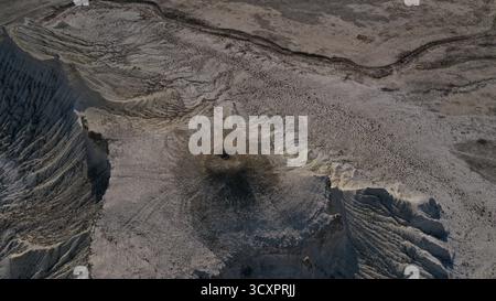 Arido paesaggio desertico che rivela un terreno arido con un'erosione significativa, modellando la terra secca in schemi intricati e creando un'impa prominente Foto Stock