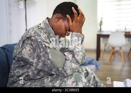 Soldato depresso affetto da stress post-traumatico seduto sul divano a casa Foto Stock