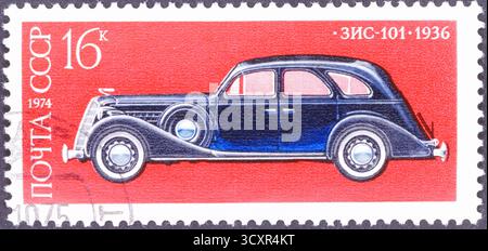 Un'automobile d'epoca blu scuro con finestre colorate di rosso è raffigurata su un francobollo rosso, con testo e numeri sovietici. Foto Stock