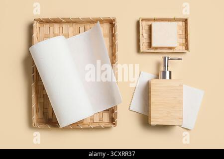 Cestello in vimini con asciugamani di carta e bottiglia di sapone su sfondo beige Foto Stock